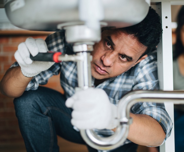 Premium Photo | Plumber fixing the kitchen sink