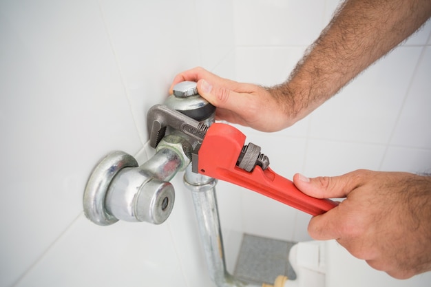 Premium Photo | Plumber fixing tap with wrench