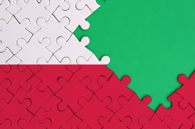 完成したジグソーパズルにポーランドの国旗が描かれています 右側に無料の緑のコピースペースがあります プレミアム写真