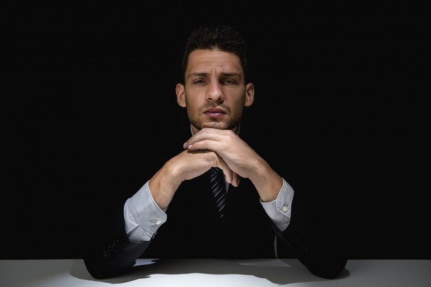 Pondering man in black suit with hands on chin in dark shadow | Premium ...