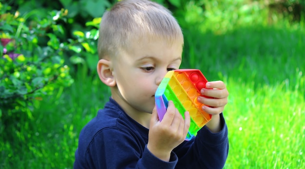 Pop it silicone anti-stress toy. the child plays on the grass. new trend selective focus. nature Premium Photo