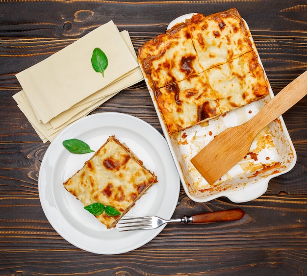 Premium Photo | Portion of tasty lasagna on wooden backgound