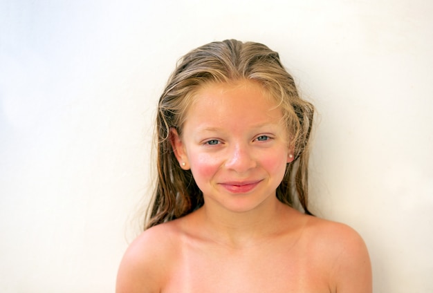  Portrait of a 9-year-old girl with long wet blond hair and blue eyes, with a sunburn
