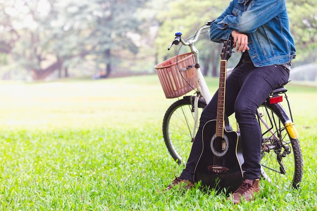 自転車に乗っている肖像画のアジアの若い男性ギター プレミアム写真