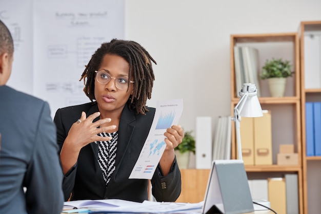 Portrait of attractive cuban woman presenting the statistical information to her unrecognizable boss Free Photo
