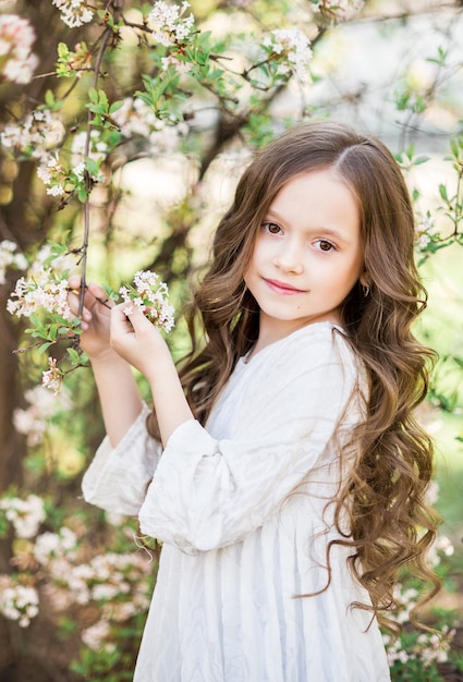 Premium Photo Portrait Of A Beautiful Baby Girl In A Spring Blooming Garden A Girl On A Background Of White Flowers