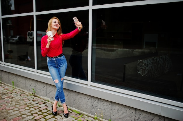 Premium Photo Portrait Of A Beautiful Woman In Red Blouse And Casual Jeans Taking Selfie On Mobile Phone And Holding A Cup Of Coffee Outside The Huge Shopping Mall