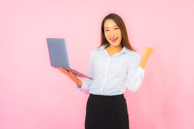 Portrait beautiful young asian woman with computer laptop on pink color wall Free Photo
