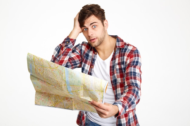 Portrait of a bewildered young man holding travel map Free Photo