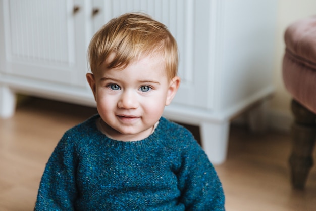 Portrait Of Blonde Little Child With Plump Cheeks Looks With Blue