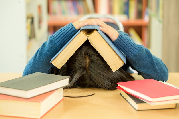 Portrait of clever student with open book reading it in college library Free Photo
