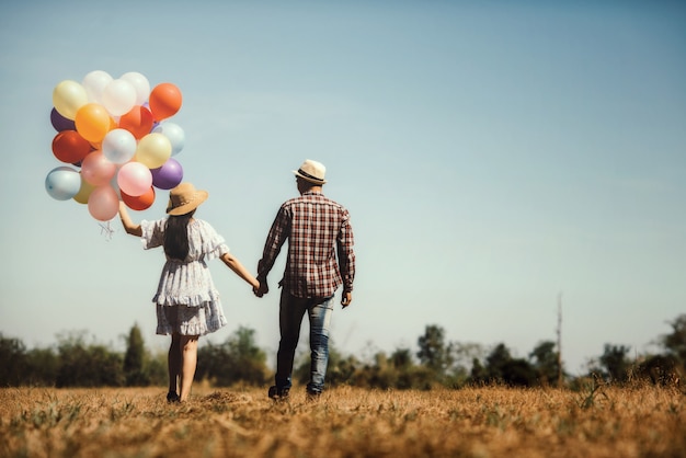 Portrait of a couple in love walking with balloons colorful Free Photo