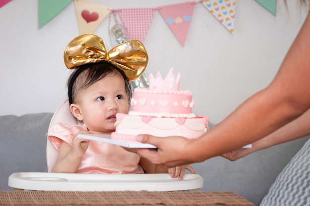 portrait cute asian baby girl celebrating her first birthday with pink princess cake parent giving birthday cake her cute daughter celebrate her first birthday 7186 3441