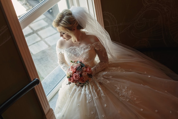 Portrait Of Cute Bride With Bridal Bouquet Of Pink Roses Indoor