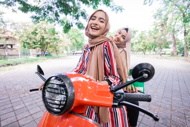 Premium Photo | Portrait of happy muslim friend riding motorcycle ...