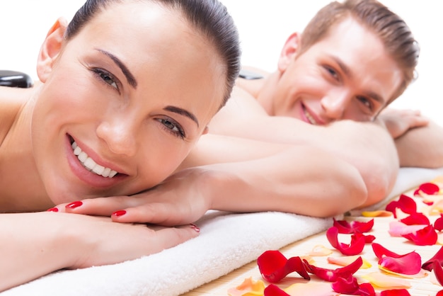 Portrait of happy smiling couple relaxing in spa salon with hot stones on body. Free Photo