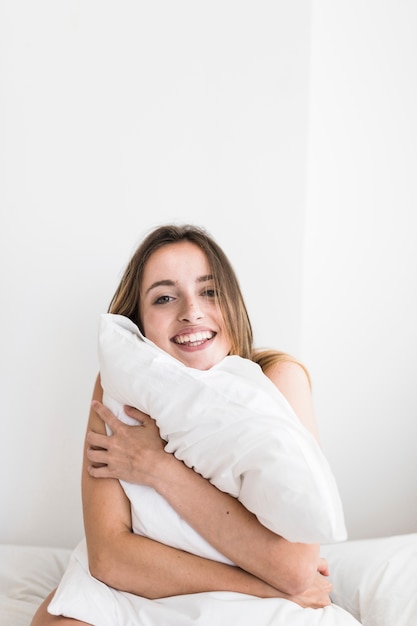 Portrait Of A Happy Young Woman Hugging Pillow Photo Free Download