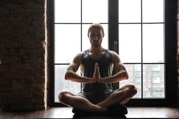 Portrait of a healthy young sportsman meditating in lotus pose Free Photo