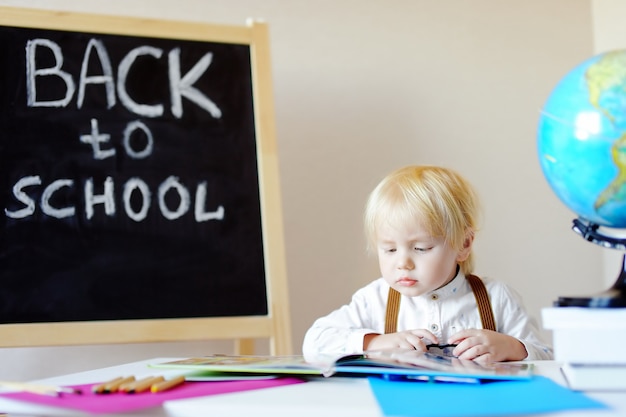 Portrait of little boy reading book at workplace. Premium Photo
