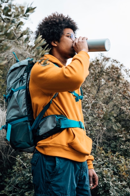 Portrait of a male hiker with his backpack drinking the water from bottle Free Photo
