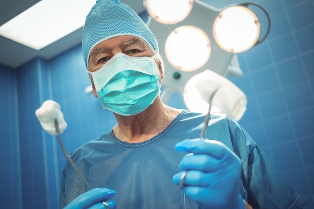 Premium Photo | Portrait of male surgeon holding surgical tools in hand