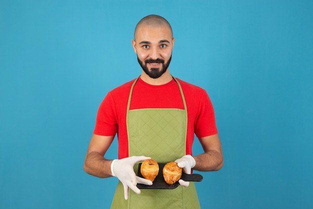 Free Photo | Portrait Of A Man In Apron And Gloves Holding Fresh Pastries