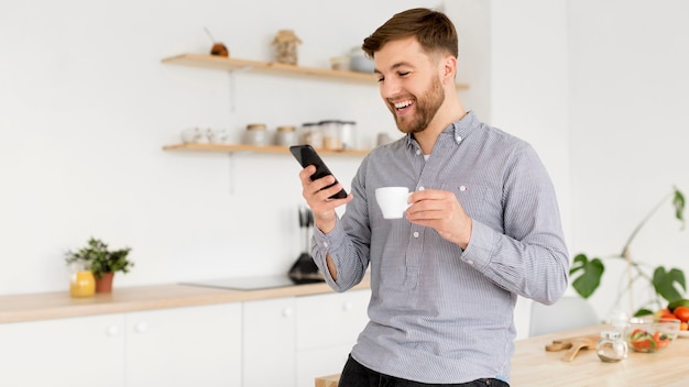 Portrait man drinking coffee while checking mobile Free Photo