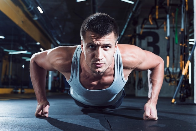 Portrait of a muscular man doing push ups in gym Photo | Free Download