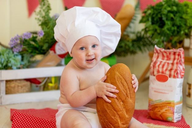 小麦粉と野菜 料理の子供 パンを食べる子供 食べ物を準備する子供と一緒に美しい写真ゾーンでパンを手にした料理人の帽子の赤ちゃんの肖像画 プレミアム写真