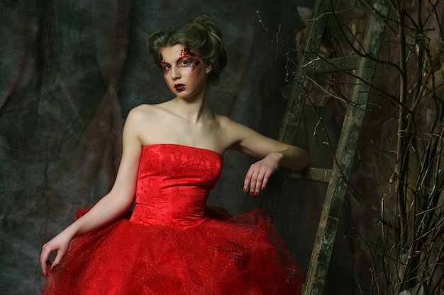 赤いドレスを着た美しい金髪の女性の肖像画 クリエイティブなメイクとヘアスタイル ファンタジーハウスで撮影 プレミアム写真
