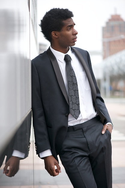 都市でビジネススーツを着ているハンサムな若い黒人の肖像 プレミアム写真