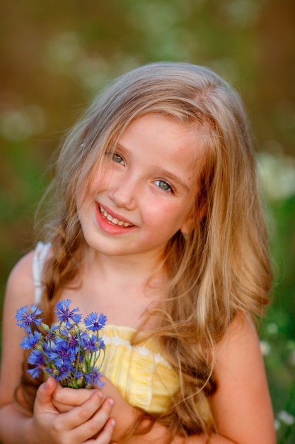 夏の野原で青い花の花束を持っている少女の肖像画 プレミアム写真