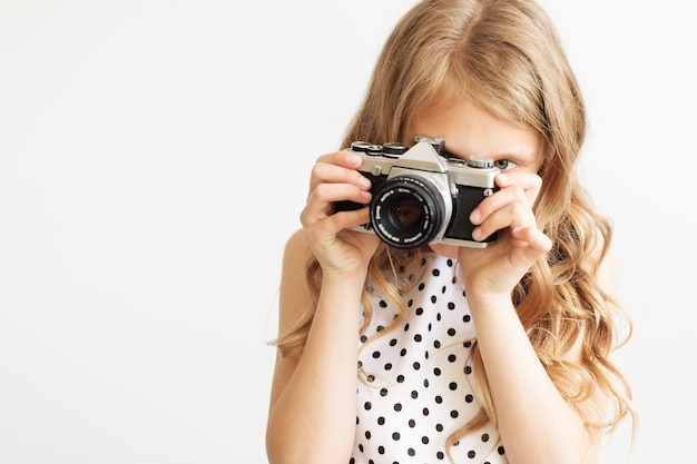 白い背景の上の古い一眼レフフィルムカメラを持つ素敵な少女の肖像画 