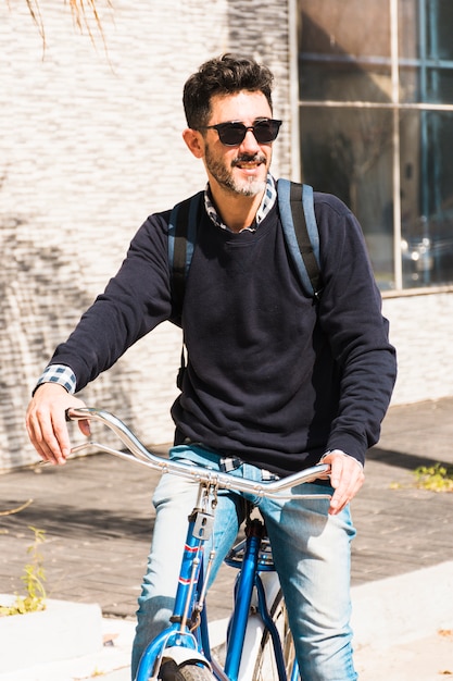 彼の自転車に乗ってサングラスをかけている笑みを浮かべて男の肖像 無料の写真
