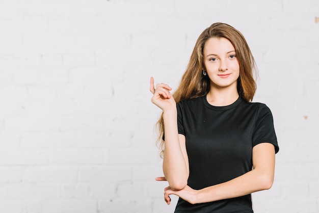 Portrait of a smiling teenage girl standing against white wall Free Photo