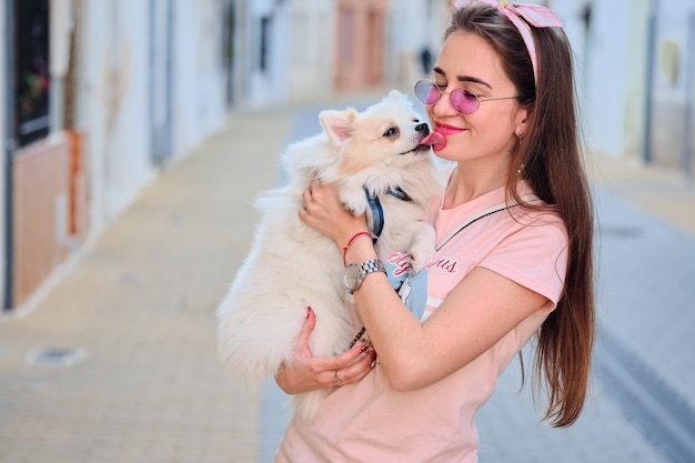 若い女の子の顔をなめる白いふわふわポメラニアン犬の肖像画 プレミアム写真