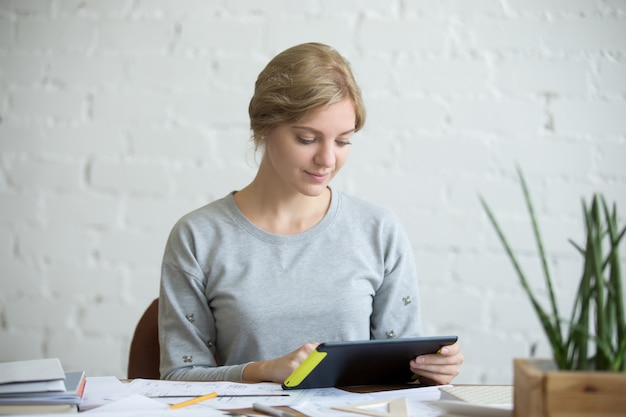 Portrait of an attractive woman with a tablet at desk  Photo | Free Download