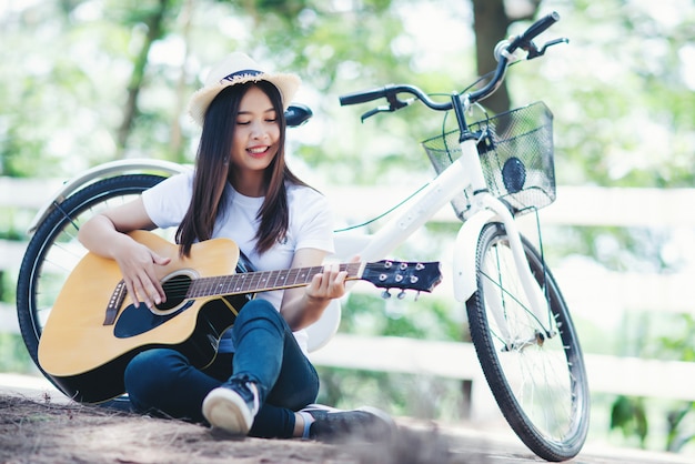 自然で自転車でギターを弾く美しい少女の肖像画 無料の写真