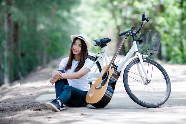 自然で自転車でギターを弾く美しい少女の肖像画 無料の写真