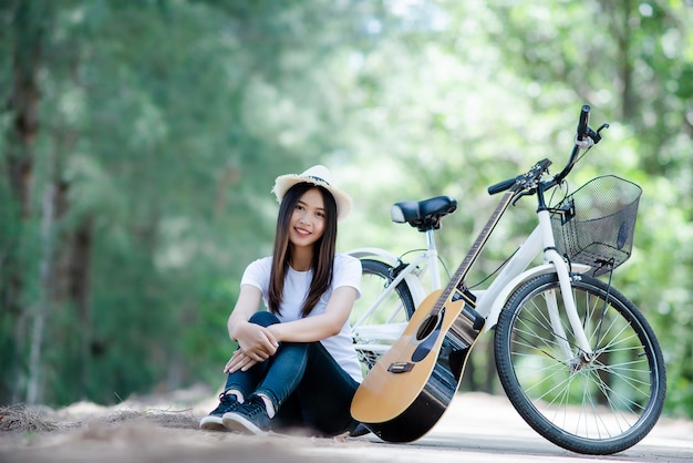 自然で自転車でギターを弾く美しい少女の肖像画 無料の写真