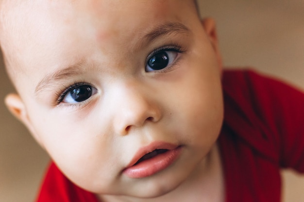 かわいい赤ちゃんのクローズアップの肖像画 かわいらしい幼児がカメラに見えます 茶色の目と長いまつ毛の禿げた赤ちゃん プレミアム写真