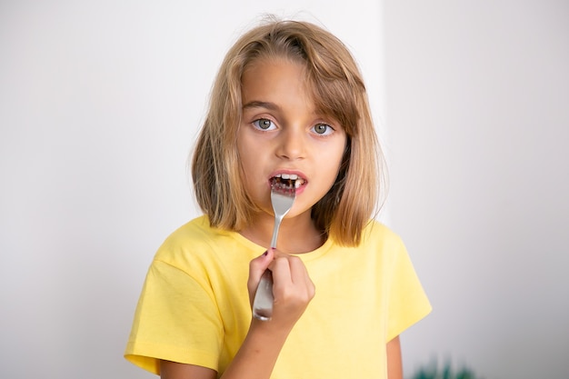 フォークでケーキを食べるかわいいブロンドの女の子の肖像画 立って 食べて かなり白人の子供 子供の頃 お祝い 休日の概念 無料の写真