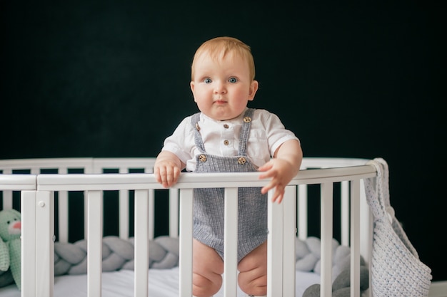 ベビーベッドで立っている面白い赤ちゃんの肖像画 プレミアム写真