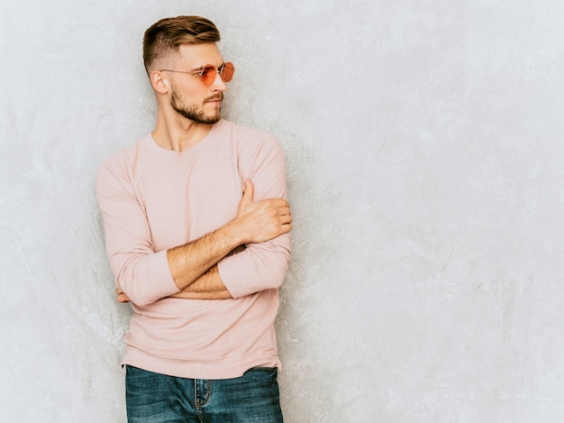 カジュアルな夏のピンクの服を着てハンサムな笑みを浮かべて若い男モデルの肖像画 丸いサングラスでポーズをとってファッションスタイリッシュな男 無料の写真