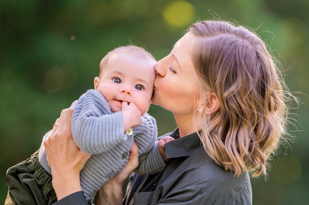 夏の公園で彼女の赤ちゃんにキス幸せな若いお母さんの肖像画 プレミアム写真