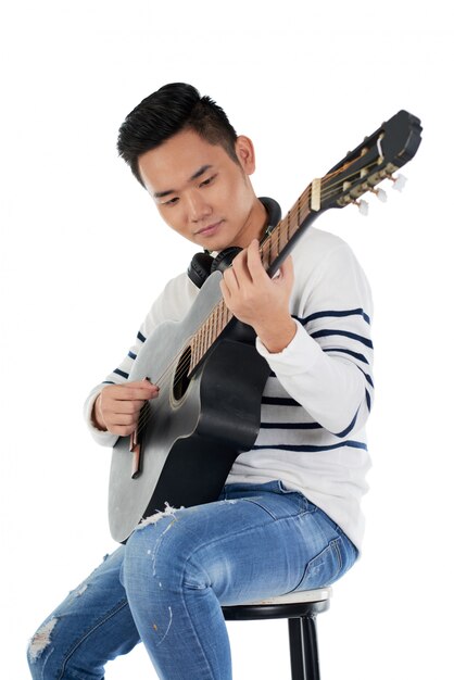 ギターを弾くスツールに座っている男性ミュージシャンの肖像画 無料の写真