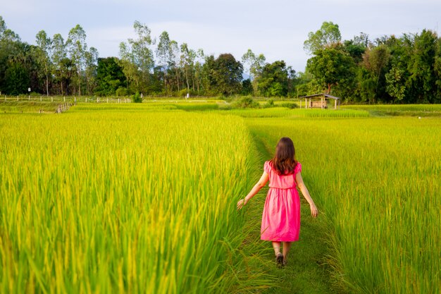 田んぼや田舎の草原で楽しんでいるピンクのドレスでかなりアジアの少女の肖像画 プレミアム写真