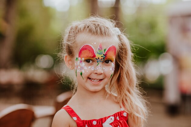 ユニコーンのような顔の絵のある白い斑点でかなり若いブロンドの女の子の肖像画 プレミアム写真