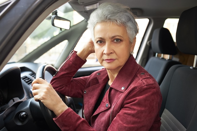 車の中に座って 運転免許試験に合格し 緊張している短い散髪の深刻な引退した女性の肖像画 無料の写真