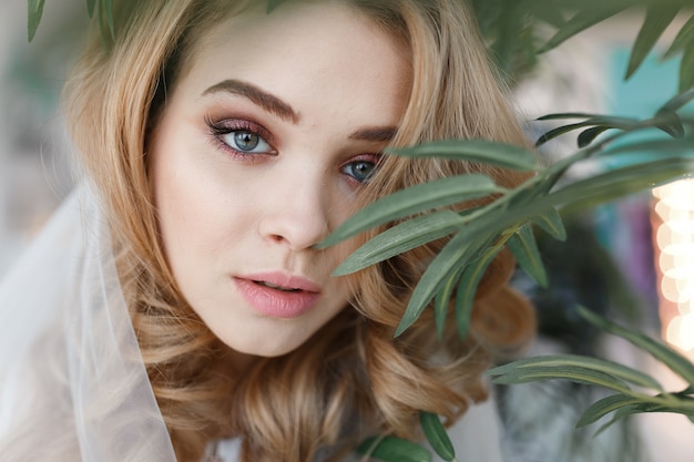 Portrait of young attractive girl with perfect skin among green leaves.  Free Photo